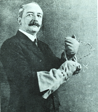 George Lynch demonstrating the special gloves he patented for handling barbed wire.