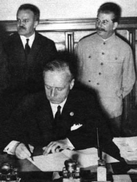 Ribbontrop, the German foreign minister, signing the Nazi–Soviet pact on 23 August 1939. Soviet foreign minister Molotov and Stalin stand in the background. (Interfoto)
