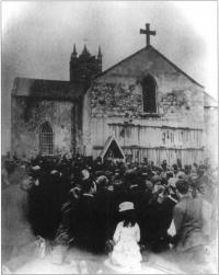An open air Mass at the shrine c.1880. Note the rows of crutches abandoned by disabled people who believed themselves cured and the extent to which the wall has been denuded of plaster by pilgrims eager for relics.(Sean Sexton collection)