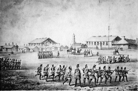 The Curragh Camp headquarters c. 1860-a group of officers and their ladies watch a section of infrantrymen drilling while another practices musketry.