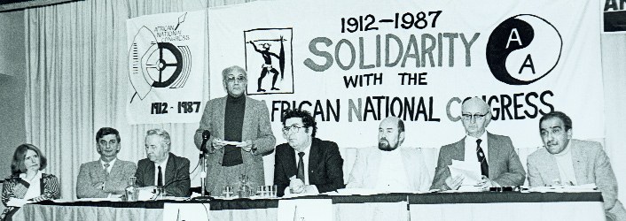 Catherine Bulbulia (Fine Gael), Niall Andrews (Fianna Fáil), Donal Nevin (Irish Congress of Trade Unions), Reg September (African National Congress), John Hume (SDLP), Ruairi Quinn (Labour Party), Tomás MacGiolla (Workers' Party) and Kader Asmal (IAAM) share a platform to celebrate the 75th anniversary of the African National Congress. From the start Asmal's intention was that the Irish Anti-Apartheid Movement should aim to acquire broad appeal, led as much as possible by well-known local personalities. (An Phoblacht)