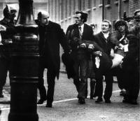 Father (later Bishop) Edward Daly waving a bloody handkerchief as he and several others carry the fatally wounded seventeen-year-old Jackie Duddy past British soldiers on Bloody Sunday. (Stanley Matchett)